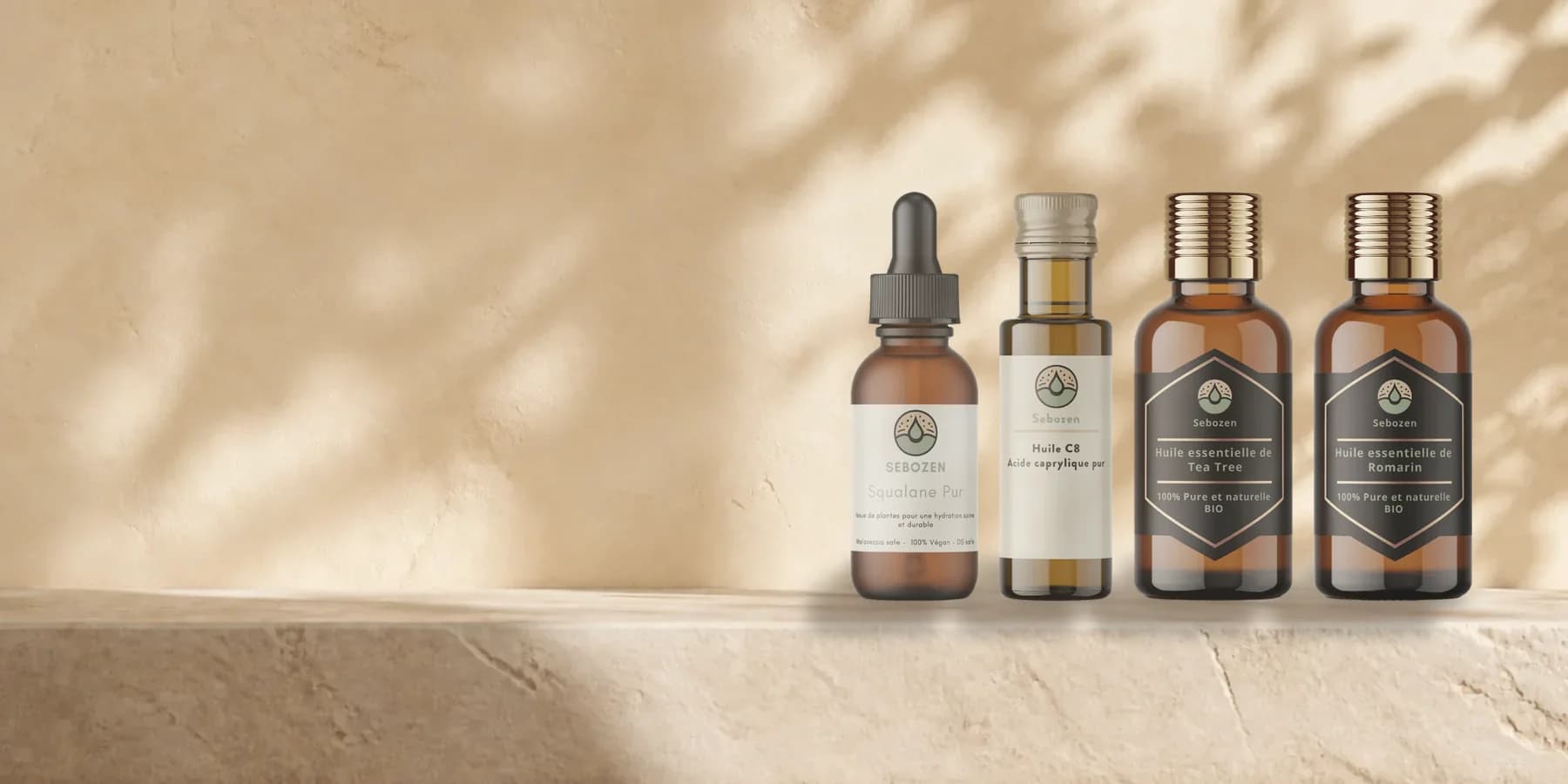 Huile C8, squalane, huile essentielle de tea tree et de romarin Sebozen alignés sur une tablette en pierre claire